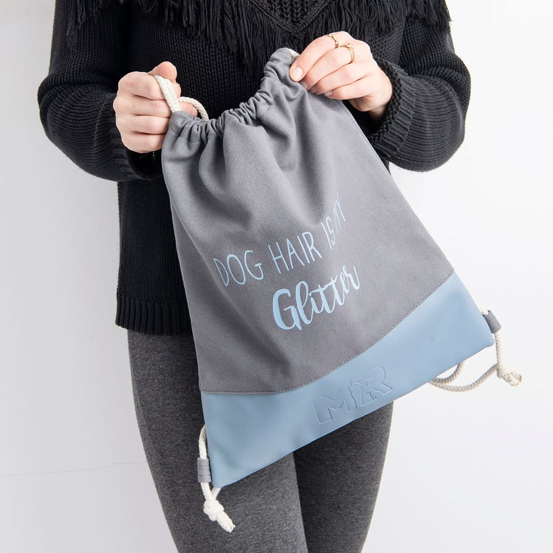 Frau trägt den Rucksackbeutel "Glitter" in der Farbkombination Grau/Hellblau in den Händen 