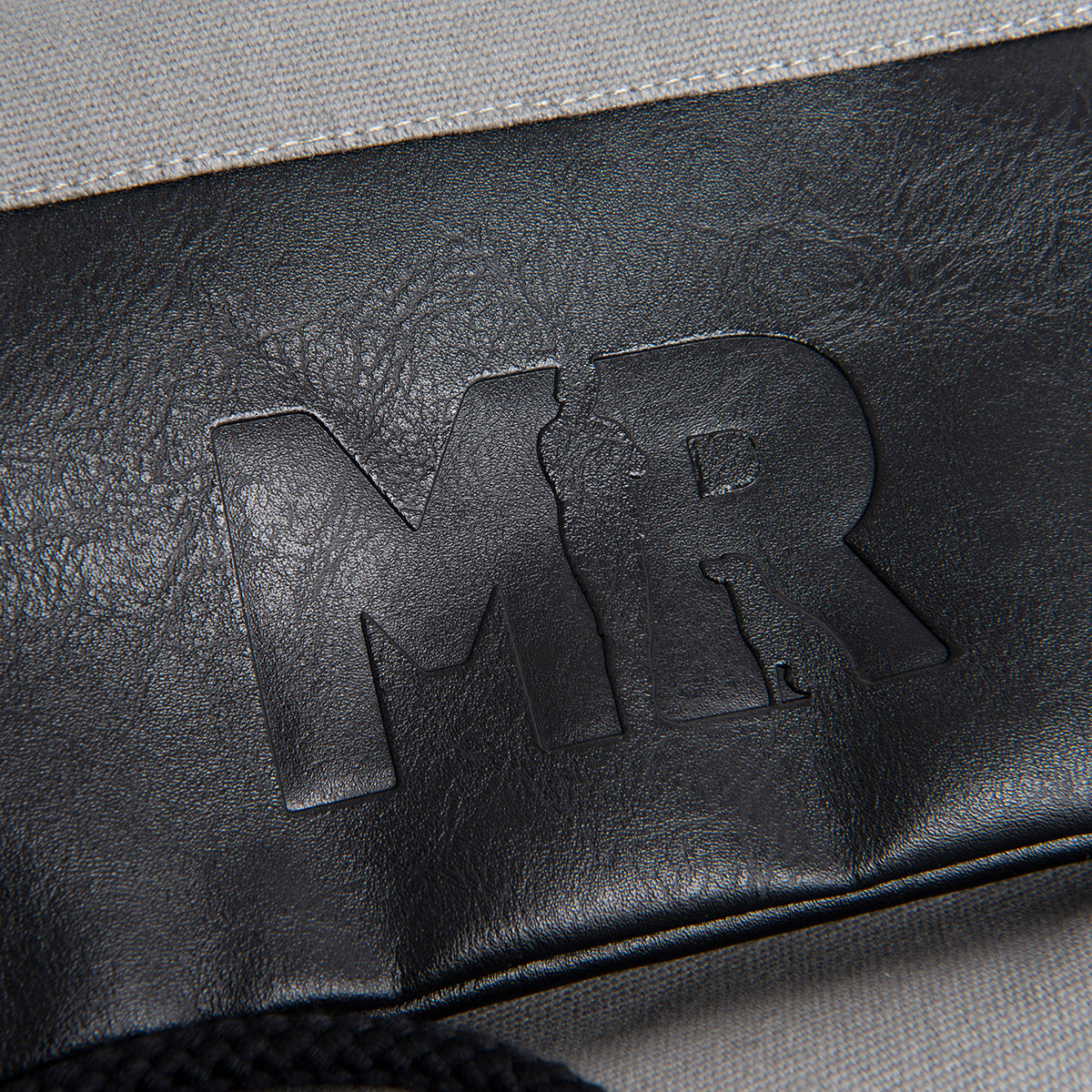 Fokus auf dem geprägtem Martin Rütter Logo auf dem unteren Bereich des Rucksackbeutels aus schwarzem Kunstleder 