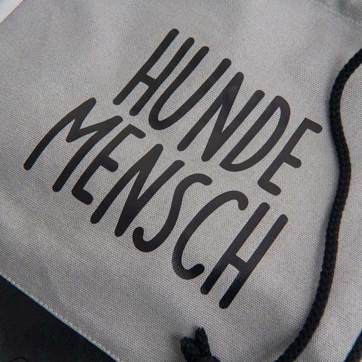 Fokus auf dem oberen Teil des Rucksackbeutels aus 100% Canvas mit dem schwarzen Aufdruck "Hundemensch" 